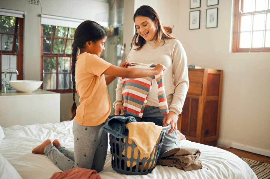 Laundry, pregnant mother and child help with house chores and cleaning with love and care. Folding
